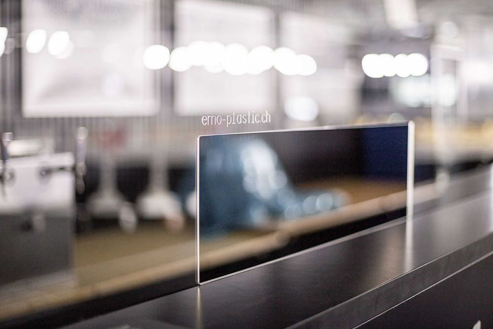 Plexiglas-Schutzscheibe mit Gravur «emo-plastic.ch» auf einer Theke