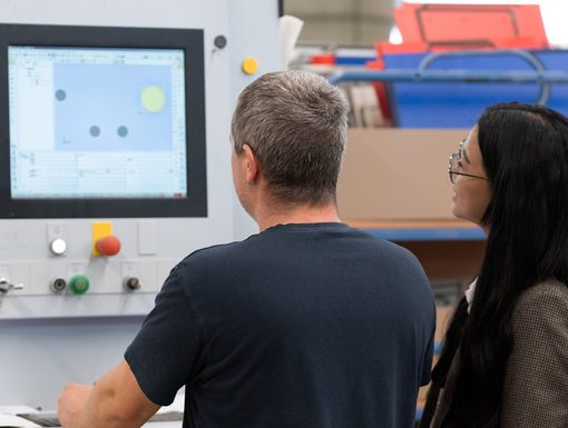 Zwei Mitarbeitende besprechen ein CNC-Programm am Maschinenbildschirm